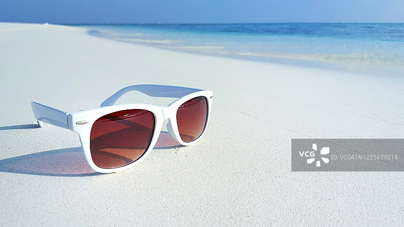 夏天放在沙滩上的白色太阳镜图片素材