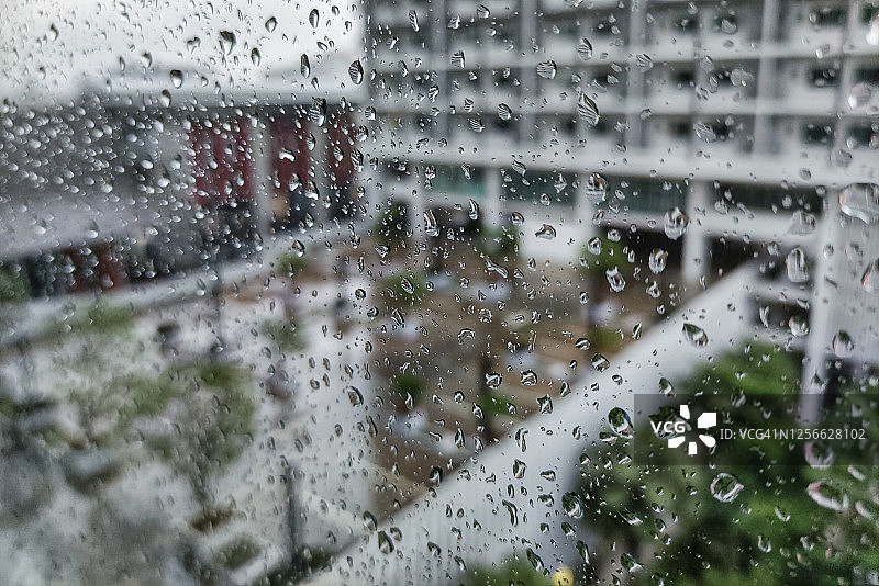 城市现代公寓大楼的停车场在雷雨期间。下雨的城市。水花飞溅在玻璃窗正面。图片素材