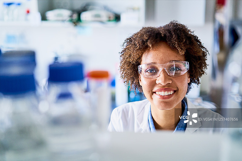 微笑的年轻女科学家站在一个实验室的架子旁图片素材