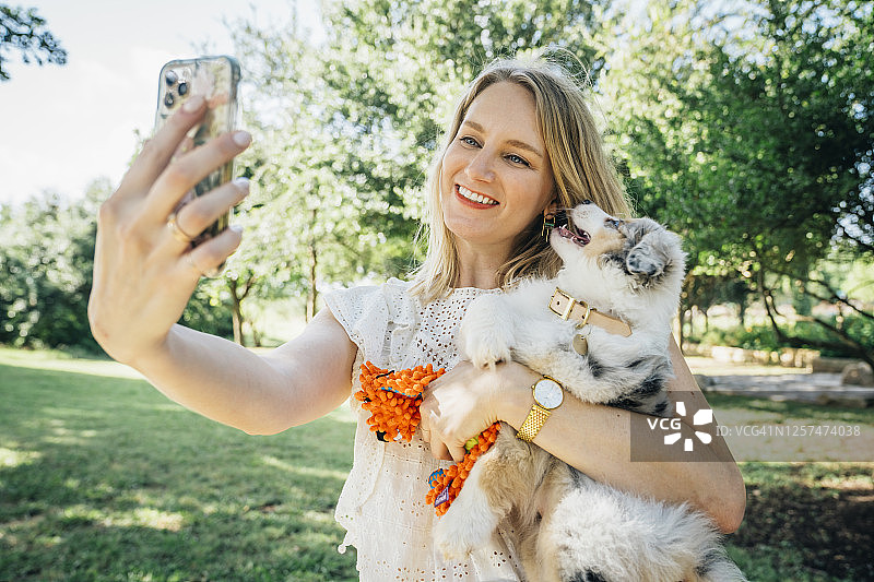 一名女子拿着澳大利亚牧羊犬狗用智能手机自拍图片素材