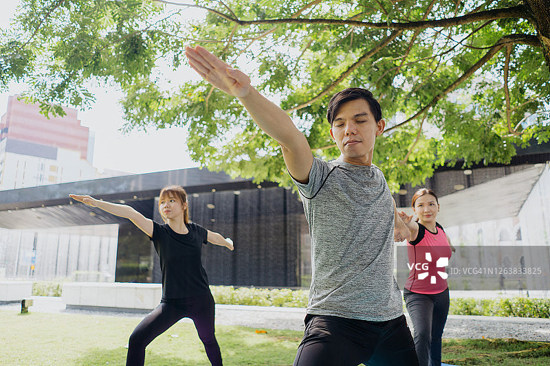 年轻的亚洲男人和女人在公共公园练习瑜伽图片素材