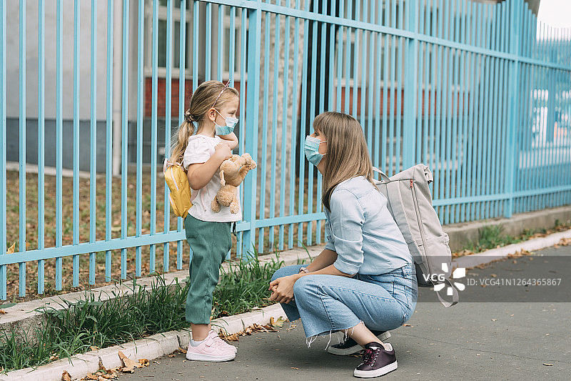 新常态:母亲和女儿戴防护口罩一起上学，冠状病毒预防理念图片素材