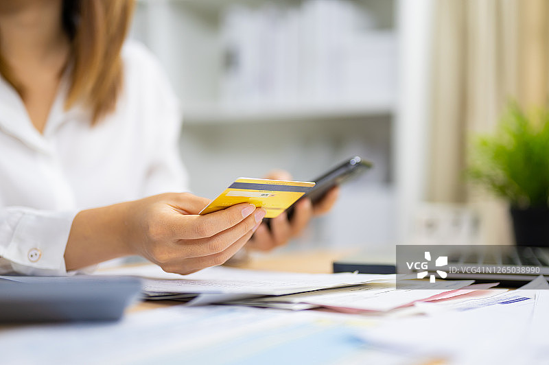 年轻女子输入信用卡信息支付网上购物支付或使用网上银行在智能手机上图片素材
