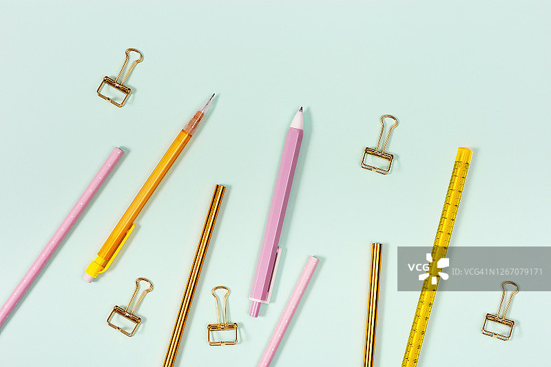 平铺学校或办公室用文具。粉色和金色的铅笔，钢笔和金属回形针。图片素材