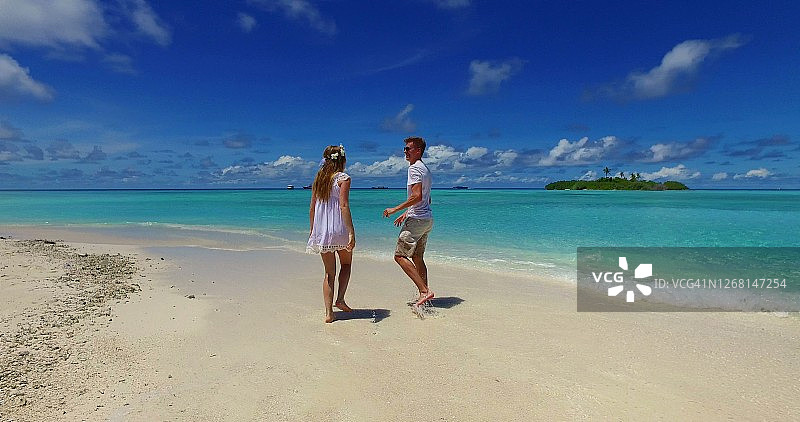 一对年轻的新婚夫妇在天堂般的沙滩上享受蜜月图片素材