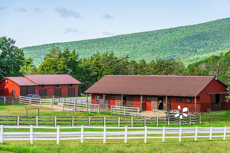 风景优美的红色谷仓在纽约州北部群山环绕。图片素材