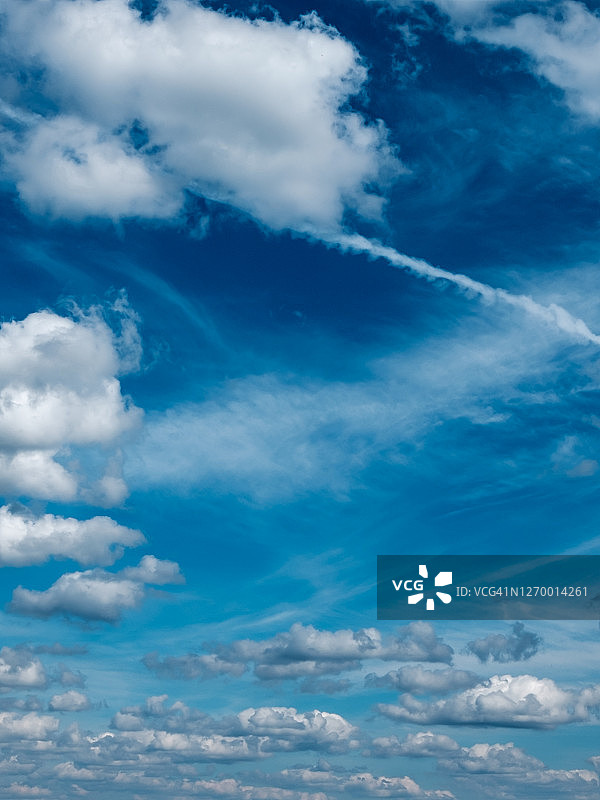 蓝天映衬着白云和薄雾。飞机在高空飞行时留下的凝结痕迹。水汽和冰晶的痕迹。图片素材