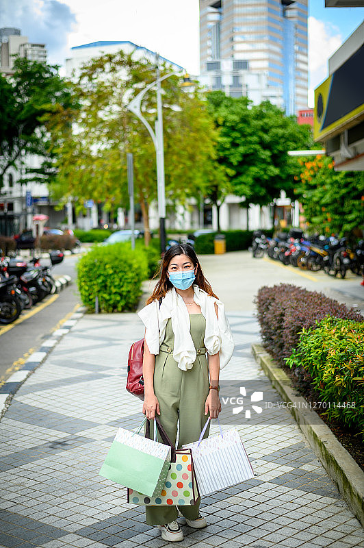 一位亚洲女游客戴着口罩在购物图片素材