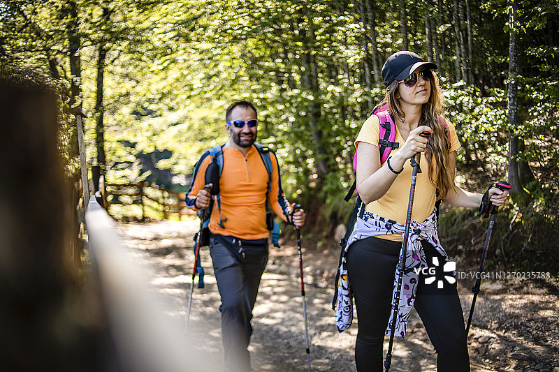 两个年轻的登山者出发去征服山顶-幸福的夫妇一起徒步旅行在山与背包-男人和女人游客步行在山图片素材