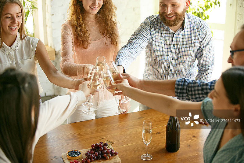 人们用葡萄酒或香槟碰杯。欢天喜地的朋友欢度节日，欢聚一堂。微笑的朋友的特写，生活方式图片素材