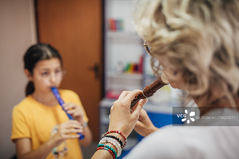 年轻的学生和她的音乐老师一起学习如何吹笛子图片素材
