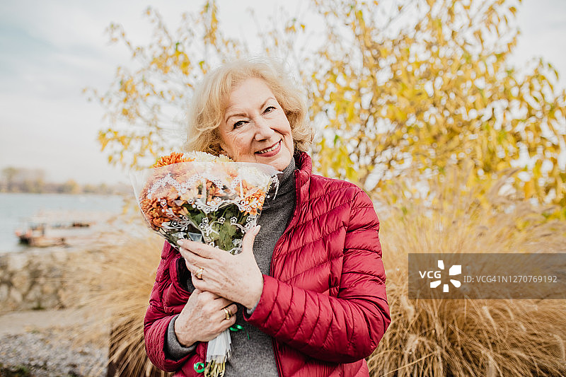 公园里一位老妇人手捧鲜花的肖像图片素材