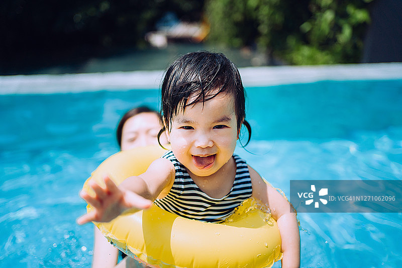 快乐的亚洲蹒跚学步的女孩愉快地微笑，享受家庭团聚的时间与母亲有乐趣的游泳池在夏天图片素材