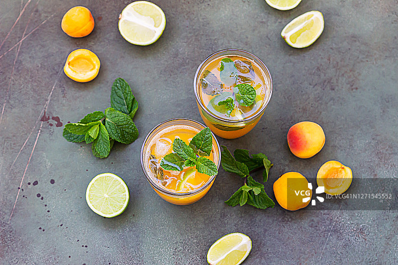 酒杯上点缀着杏子、薄荷和酸橙的清新鸡尾酒。冷鸡尾酒或冰茶。图片素材