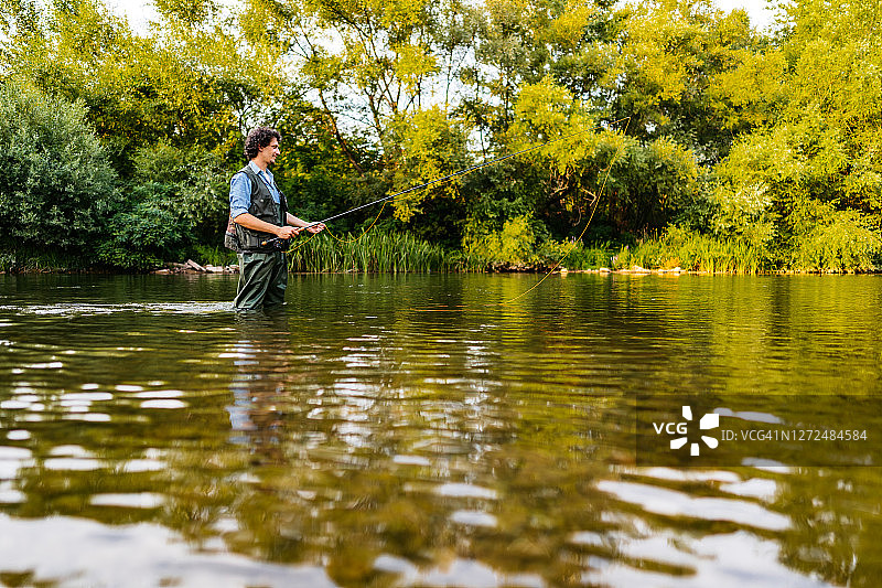 在森林河中钓鱼的渔夫图片素材
