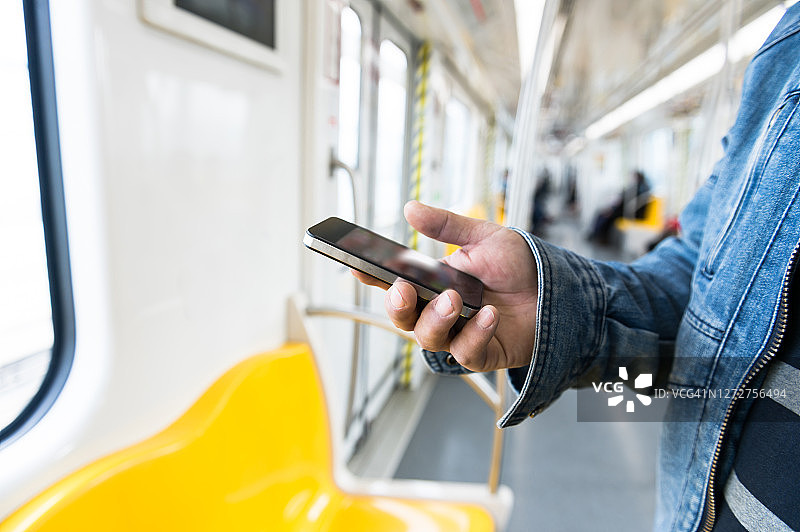 一个亚洲男人在地铁里玩手机图片素材