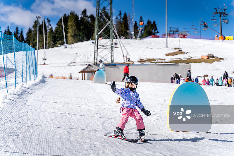 年轻的滑雪女孩学习如何滑雪和有乐趣的滑雪坡图片素材