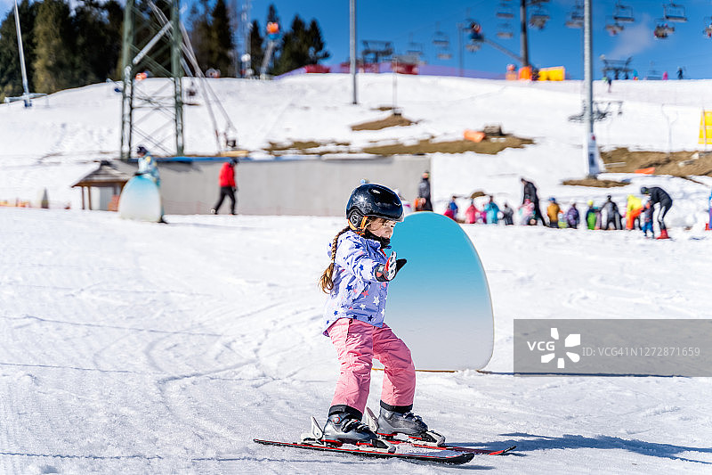 年轻的滑雪女孩学习如何滑雪和有乐趣的滑雪坡图片素材