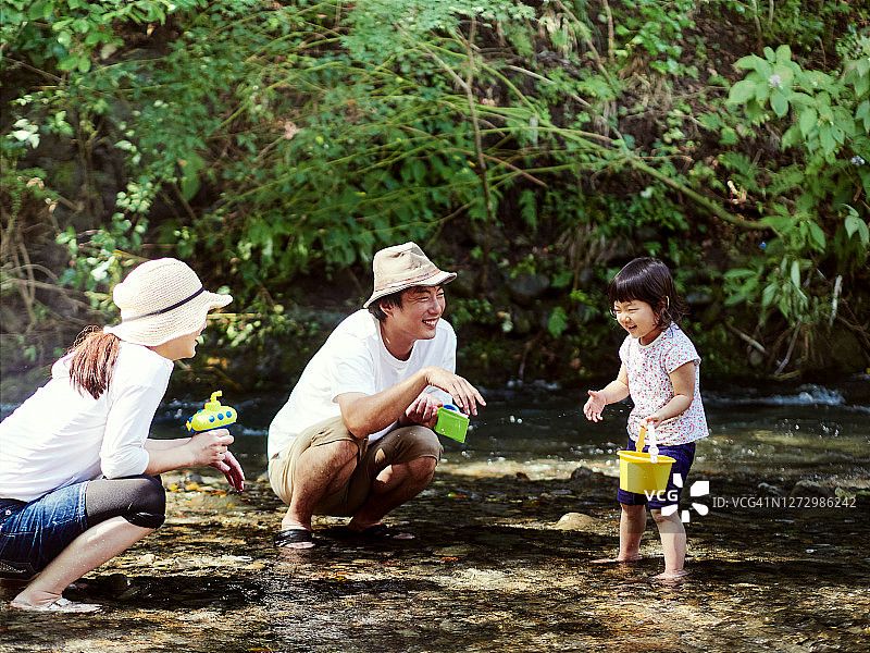 三个父母和孩子在河里玩。图片素材