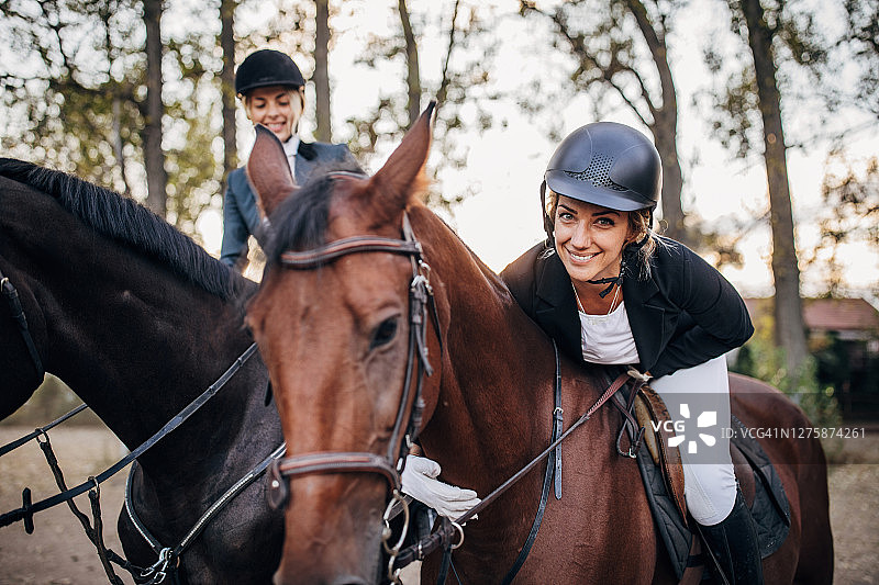 两位快乐的女骑手在户外马术场上骑马图片素材