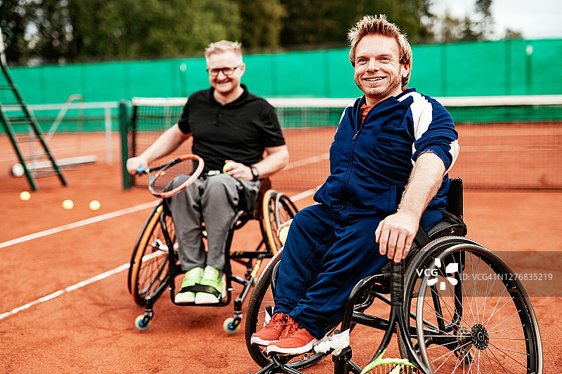 坐在轮椅上的男子在户外打网球——残疾人运动员对着镜头微笑图片素材