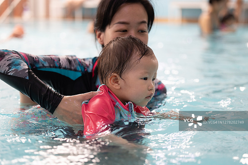 亚洲母亲和婴儿在游泳池，学习如何划水图片素材