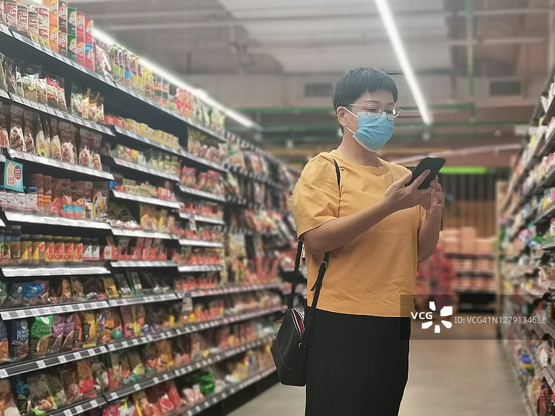 一位亚洲华人女性戴着口罩去超市买菜图片素材
