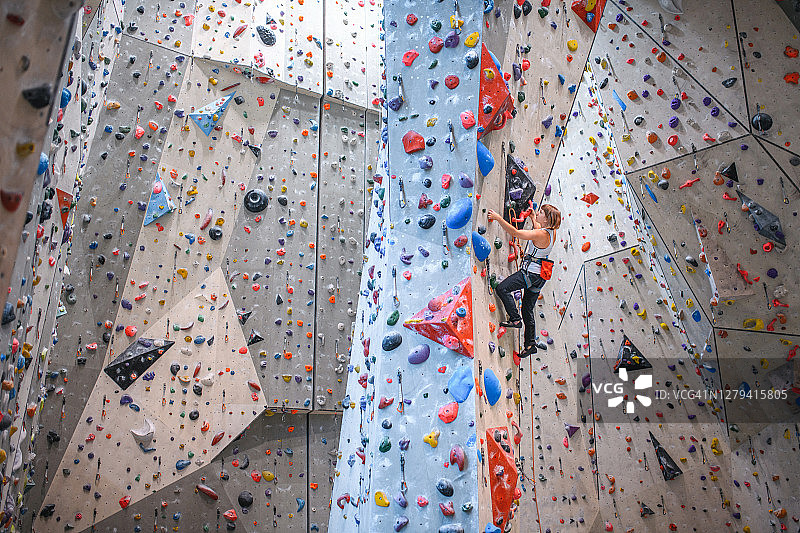 20岁出头的女人在攀岩馆攀爬垂直墙图片素材