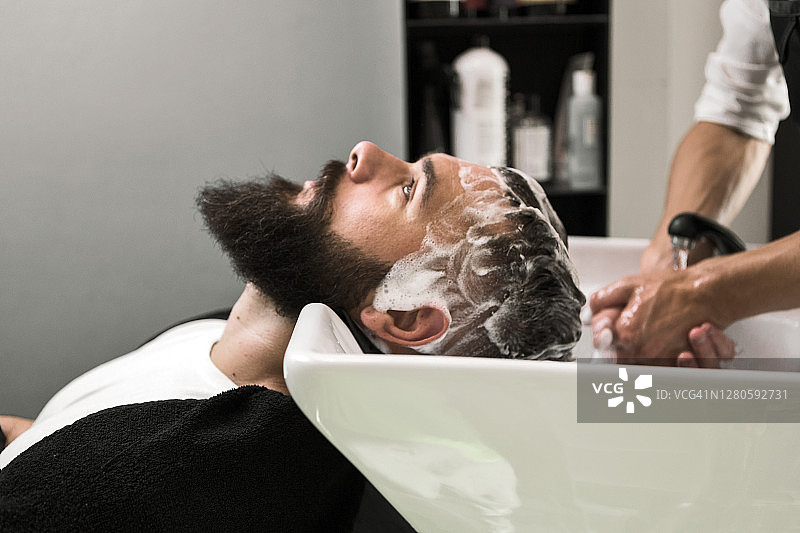 一个年轻人在理发师面前洗头的侧视图图片素材