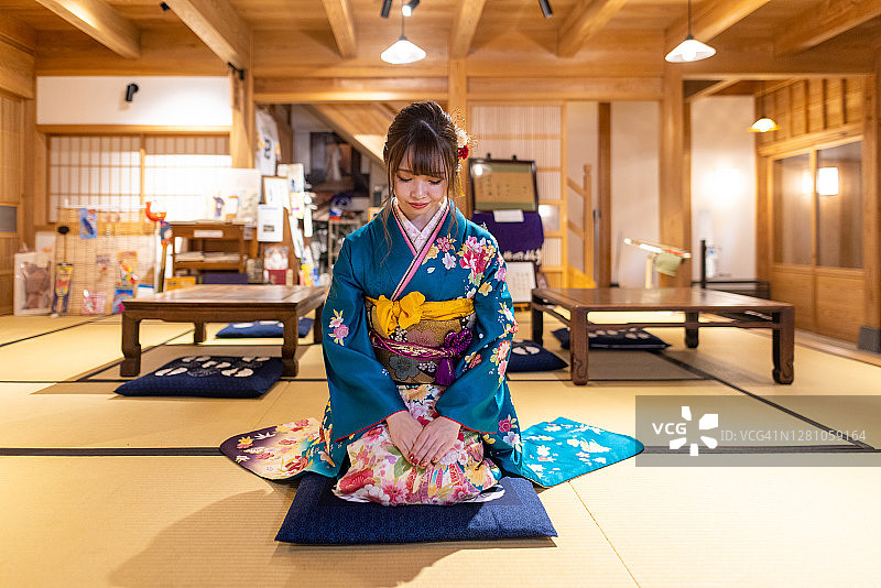 年轻女子在“Furisode”和服坐在高跟鞋在日本榻榻米房间图片素材