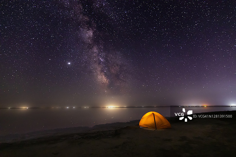 星星下沙滩上的橙色帐篷。银河系图片素材