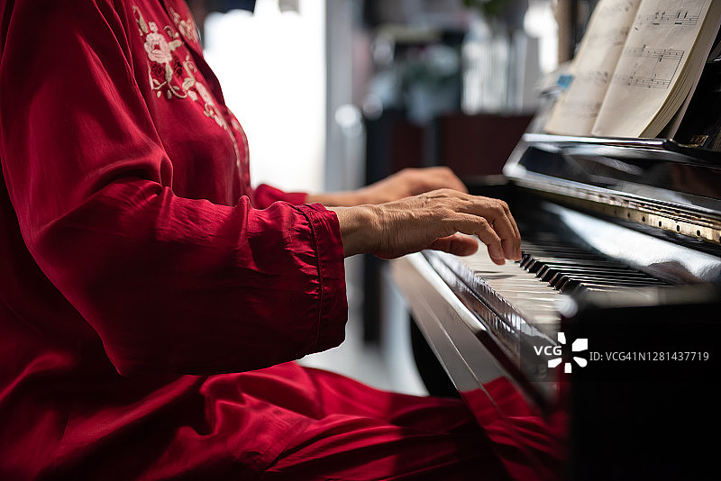 老妇人在家里弹钢琴。退休的女人图片素材