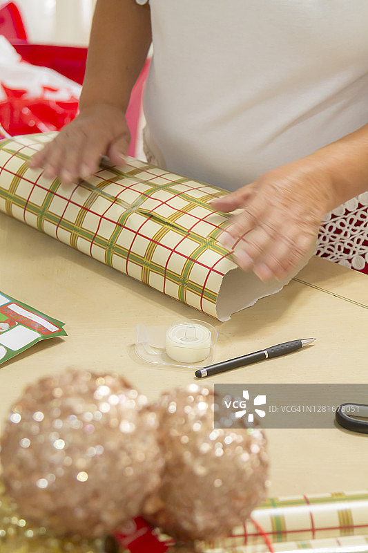 近肖像画的拉丁成熟妇女的手切割和包装圣诞礼物在拉丁家庭在美国图片素材