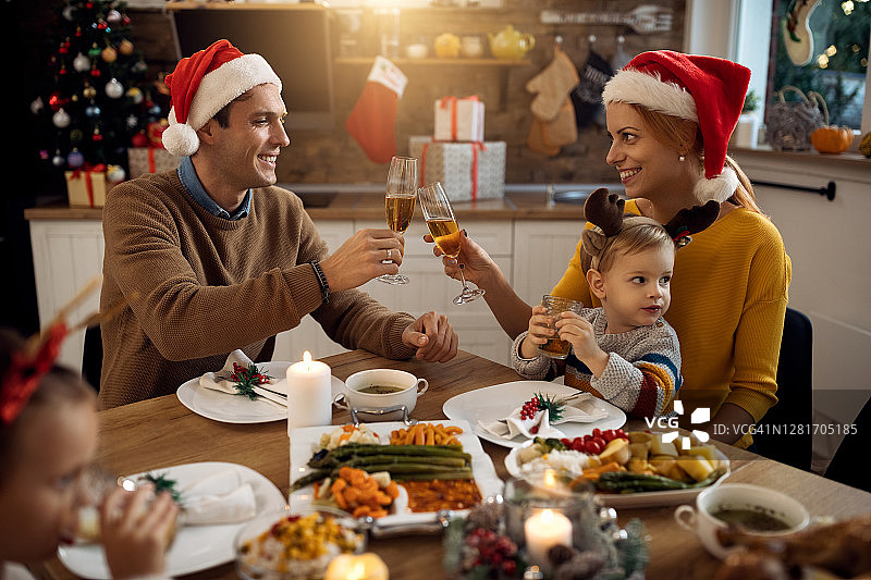快乐的父母在圣诞节家庭午餐时用香槟举杯。图片素材