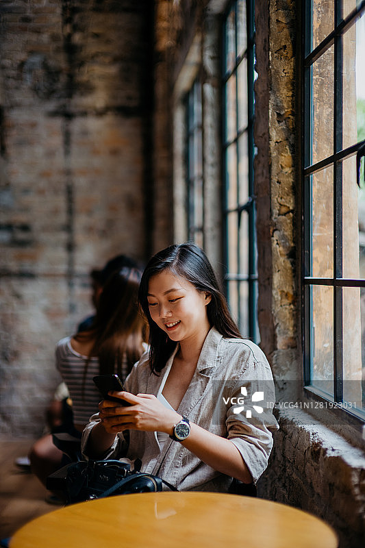 一名亚洲华裔女性在咖啡馆使用智能手机图片素材