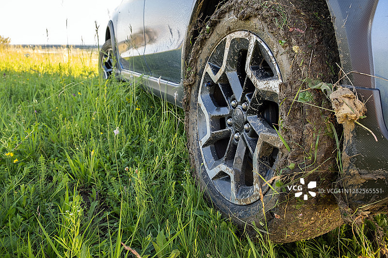 靠近肮脏的公路汽车车轮与肮脏的轮胎覆盖着黄色的泥。图片素材