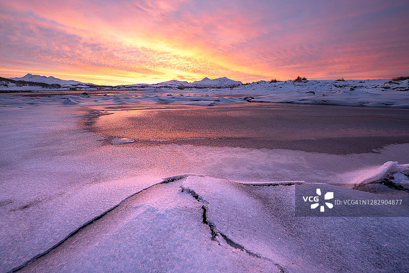 在挪威，在一个非常色彩缤纷的日出期间，沿着海岸被冰雪覆盖的景观图片素材