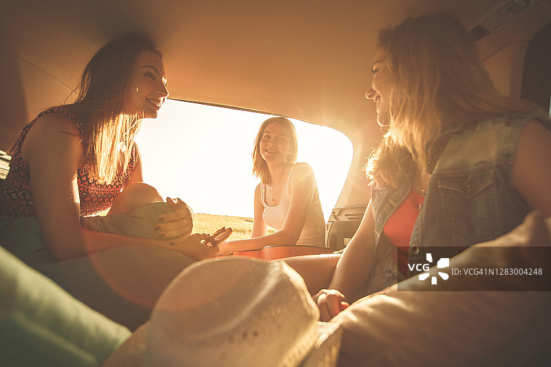夏天开车旅行时，女朋友们在汽车后备箱里玩得很开心图片素材