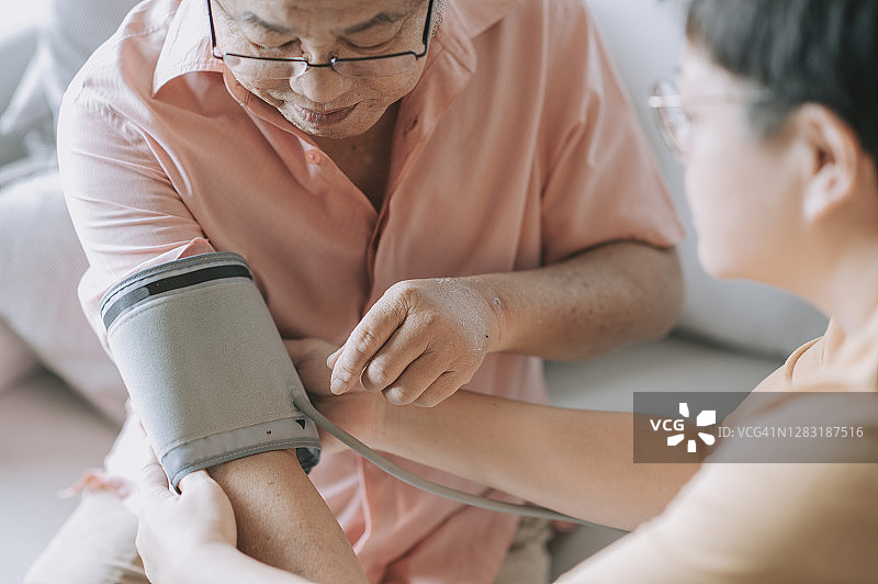 在女儿的帮助下，一名亚裔华人老人正在检查血压图片素材