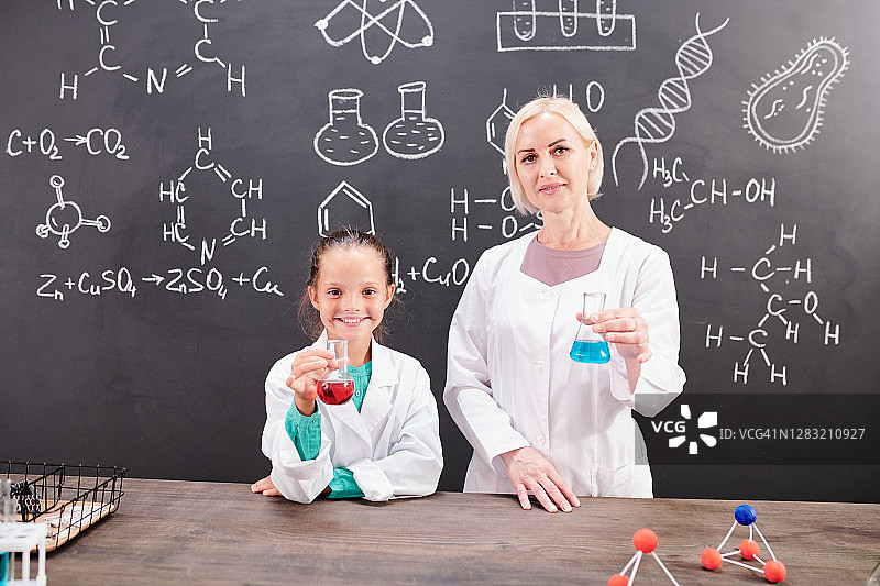 聪明的女学生和成熟的化学老师穿着白大褂拿着管子图片素材