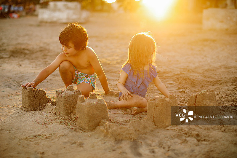 快乐的笑着蹒跚学步的男孩和女孩在沙滩上玩耍图片素材