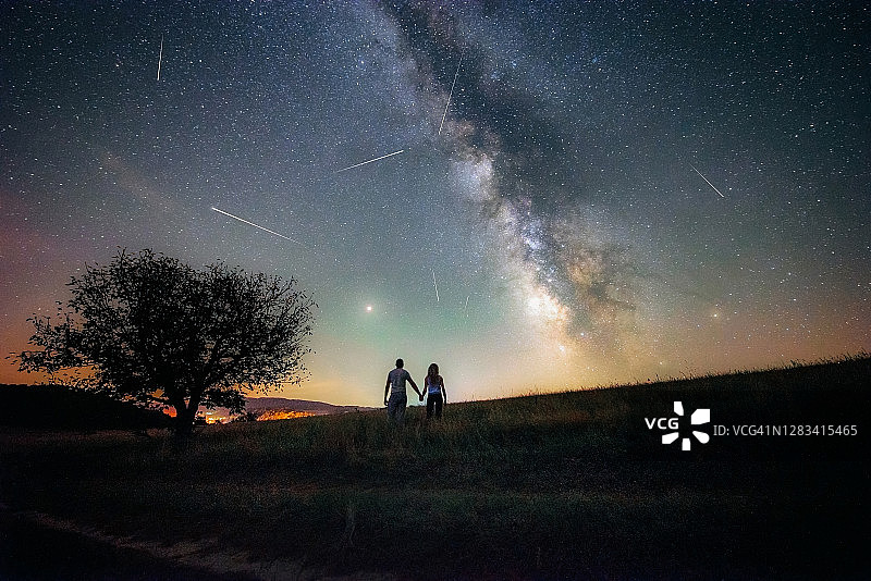 年轻夫妇观看英仙座流星雨和银河图片素材