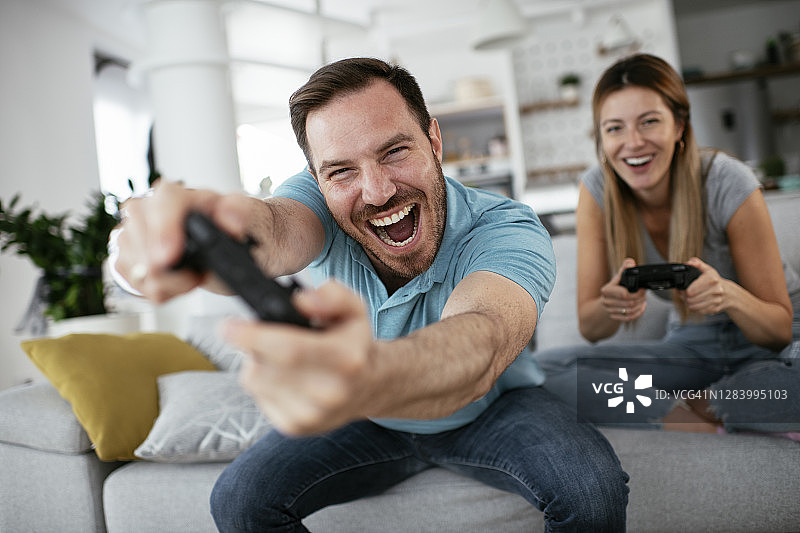 丈夫和妻子在客厅用操纵杆玩电子游戏。图片素材
