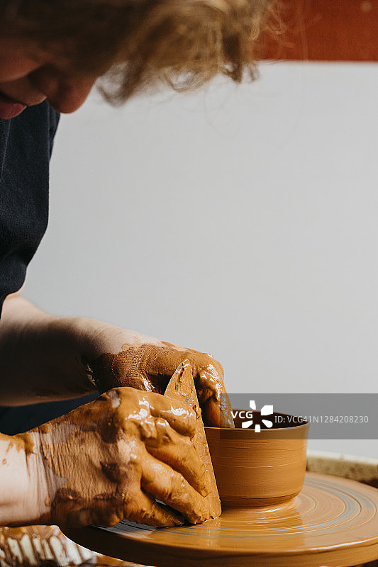 陶艺家在陶工轮上雕刻一个碗。图片素材