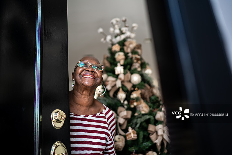 快乐老女人开门，圣诞树在背后图片素材