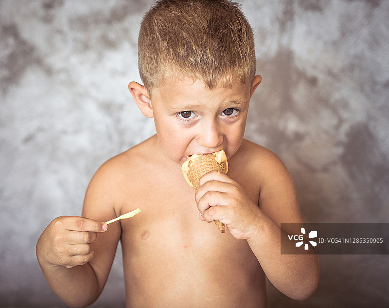 男孩喜欢吃冰淇淋，在家里微笑图片素材