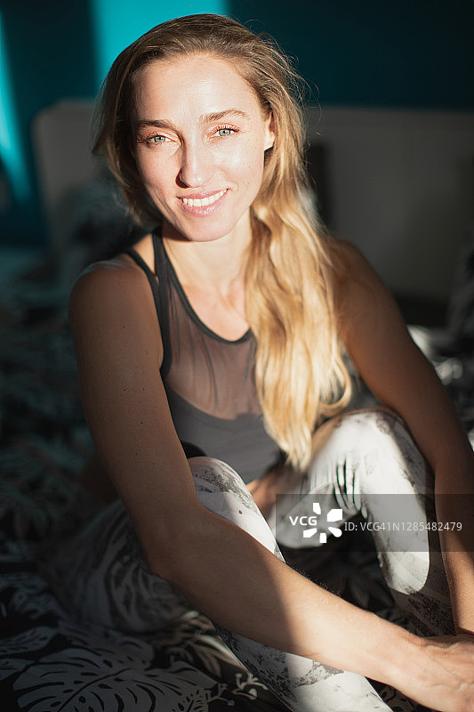 穿着瑜伽服坐在床上的快乐女人图片素材
