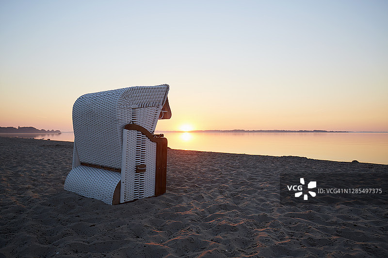 日出时坐在海边的柳条沙滩椅上图片素材