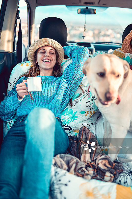 可爱的女性放松与狗在小货车后面喝着茶图片素材