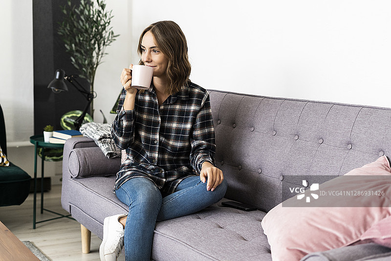 坐在家里沙发上喝咖啡的女人图片素材